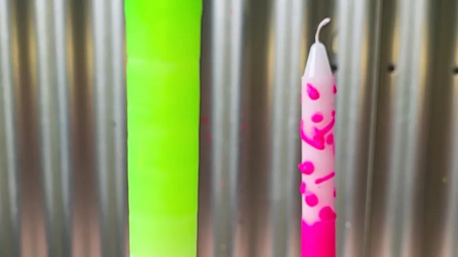 Two colorful candles on striped background.