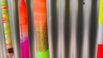 Bunte Stifte hängen vor metallischem Hintergrund.
