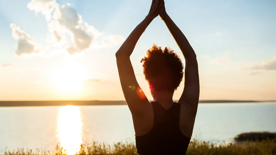 Person macht Yoga im Freien bei Sonnenuntergang.