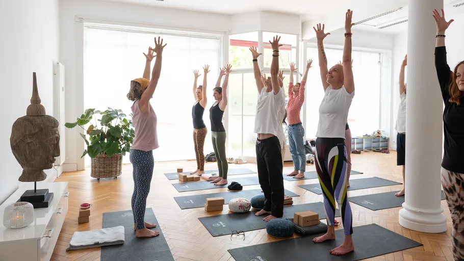 People practicing yoga poses in a studio.
