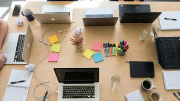 Laptops and stationery on wooden desk.