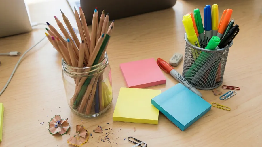 Pencils and markers on cluttered desk.