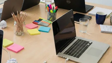 Laptops und Schreibwaren auf einem Holztisch.