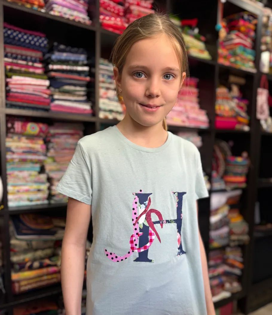 Girl smiling in front of fabric shelves.