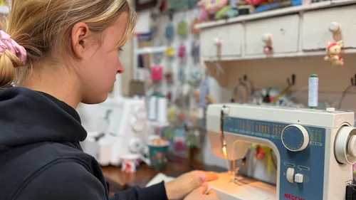 Person sewing at sewing machine in workshop.