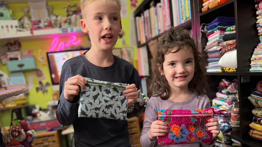 Zwei Kinder halten bunte Taschen in einem Laden.