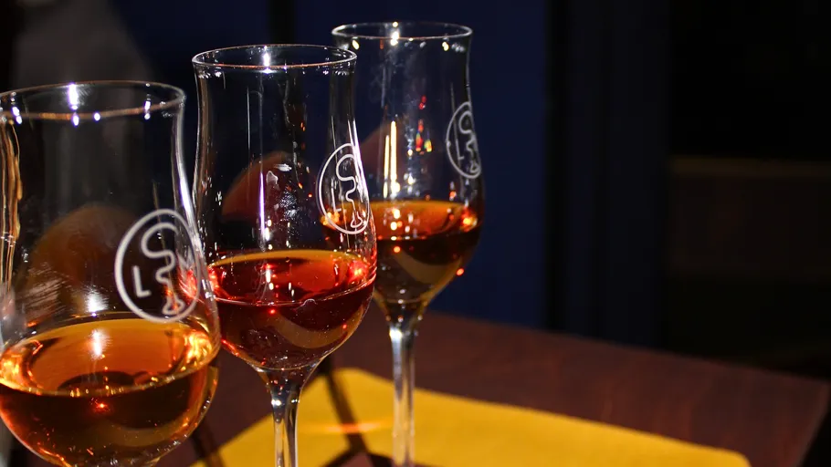 Three glasses of amber liquid on table.