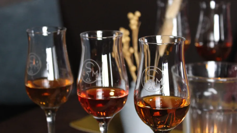 Three whiskey glasses on a wooden table.