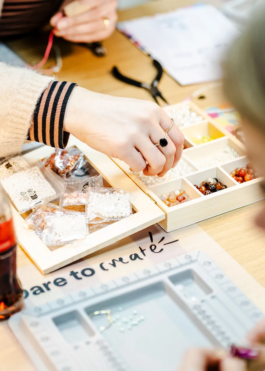 Hand selecting beads from a craft box.