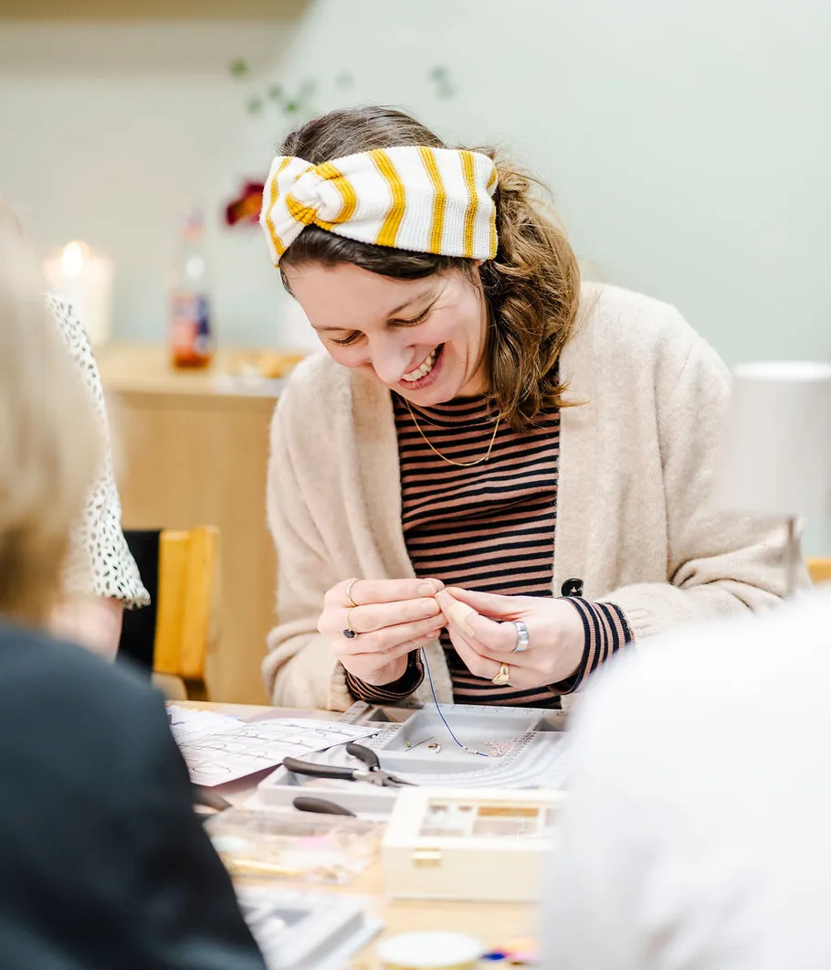 Lächelnde Frau bastelt an einem Tisch.