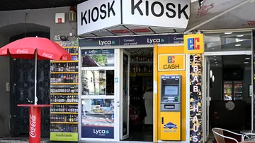 Kiosk-Eingang mit Getränken und Geldautomat draußen.