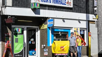 Menschen stehen vor einem Kiosk mit Hermes-Schild.