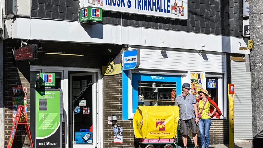 People standing outside kiosk with Hermes sign.