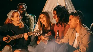 Group of friends playing music by a tent.