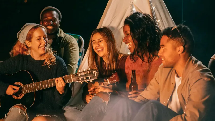 Group of friends playing music by a tent.