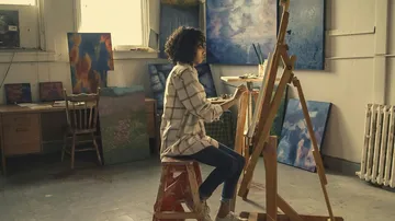 Artist painting on canvas in studio.