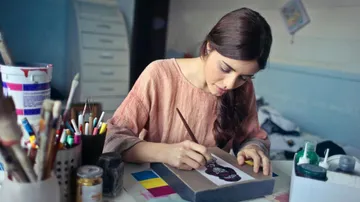 Woman painting artwork in creative studio.