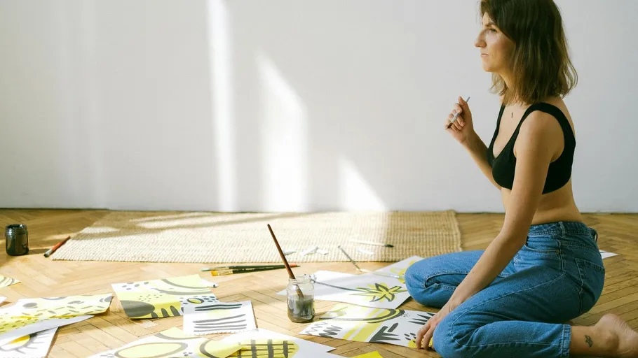 Woman painting on floor with art supplies.