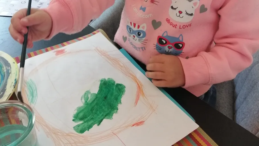 Child painting on paper at table.