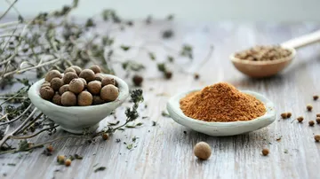 Schalen mit ganzen und gemahlenen Piment auf Holztisch.