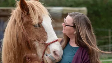 Frau zeigt Zuneigung zu Pferd im Freien.
