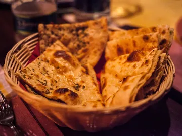 Ein Korb mit frisch gebackenem Fladenbrot auf rotem Tuch.