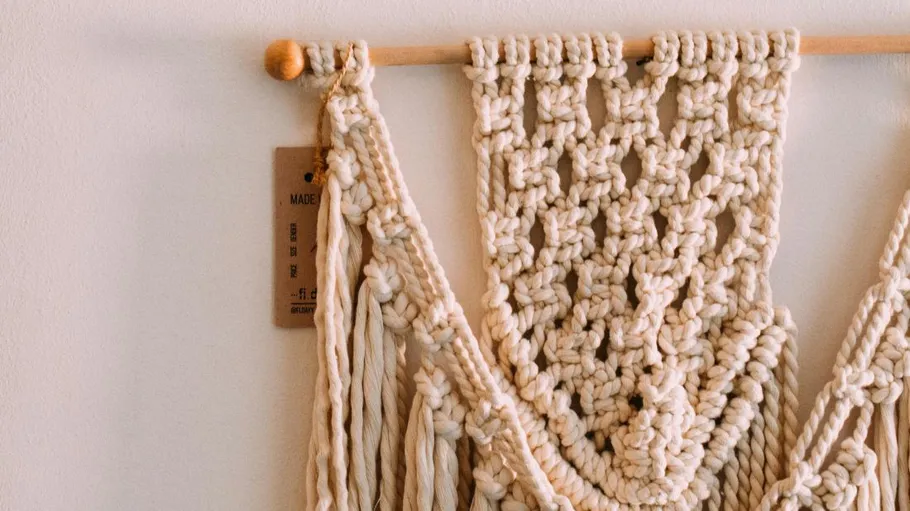 Macrame hanging on wall with wooden rod.