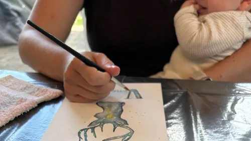 Person painting with a child on lap.