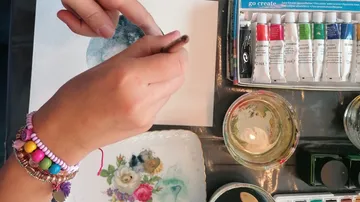 Hand malt mit Aquarellen auf Tisch.