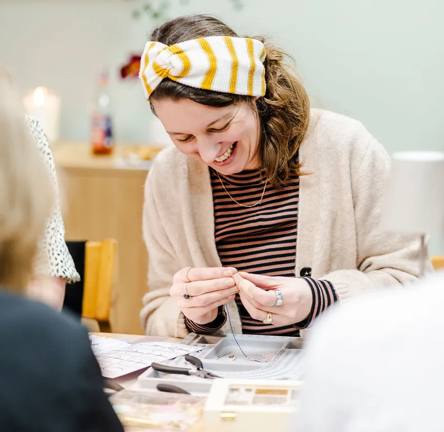 Woman crafting jewelry in workshop setting.