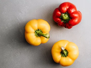 Three peppers lie on a grey surface.
