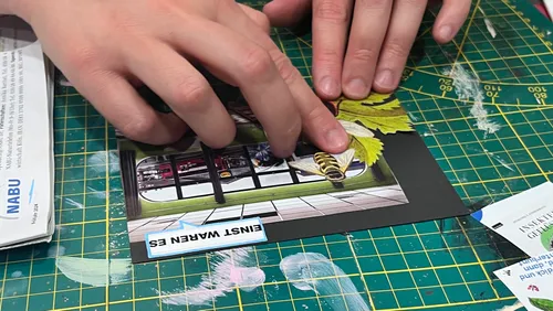 Hands assembling collage on cutting mat.