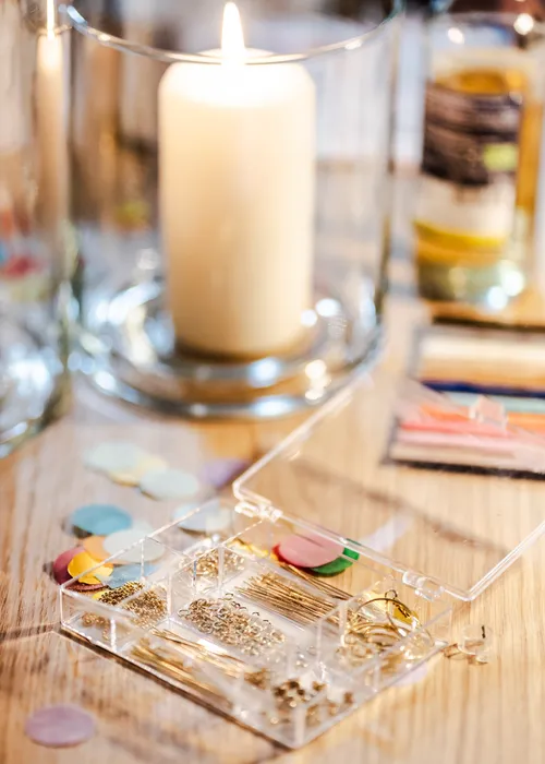 Candle, open jewelry box, scattered confetti, wooden table.