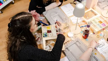 Women crafting jewelry at a workshop table.