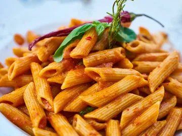 Pasta with tomato sauce, decorated with basil and chilli.