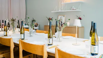 Esszimmertisch mit Weinflaschen und Blumen dekoriert.