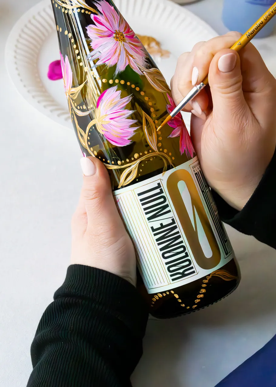 Hand malt Blumen auf Flasche mit Pinsel.