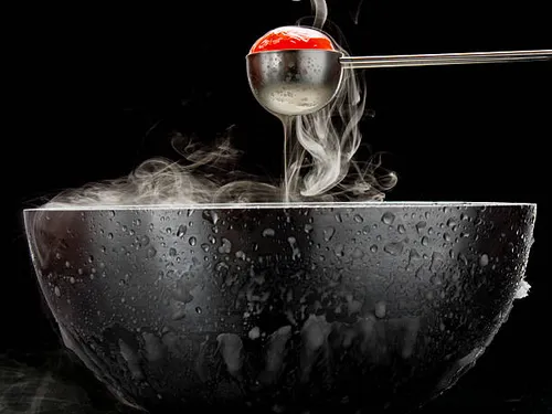 A spoon lifts a steaming tomato out of a bowl.