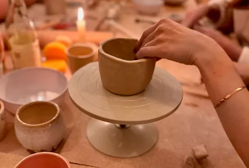 Hand shaping clay pot at pottery workshop.
