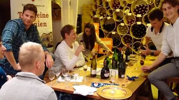 Gruppe genießt Weinprobe an Holztisch.