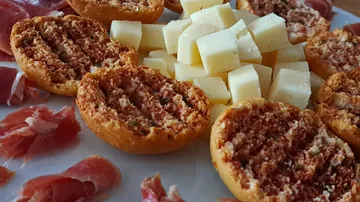 Käsewürfel, Schinken und Bruschetta auf einem Teller.