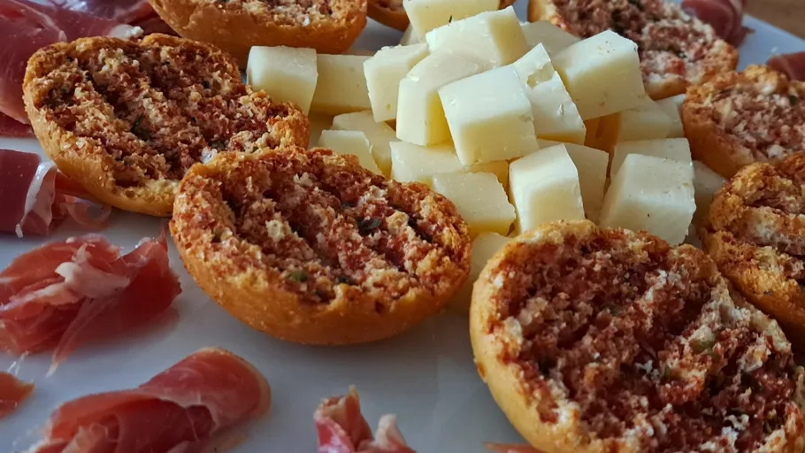 Cheese cubes, prosciutto, and bruschetta on a plate.