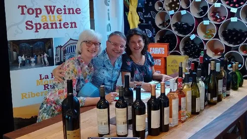 Three people behind wine display at event.