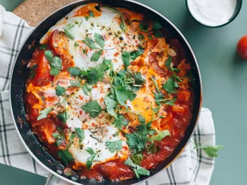 Eier in Tomatensauce, garniert mit frischen Kräutern, serviert.