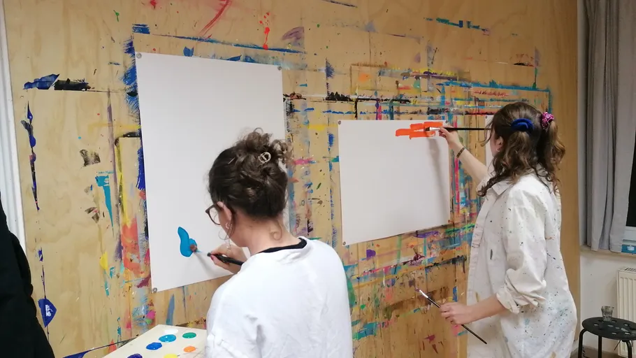 Zwei Frauen malen abstrakte Kunst auf Leinwand.