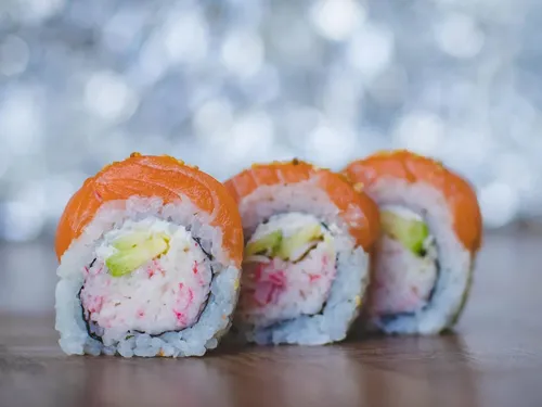 Sushirollen liegen auf einem Tisch mit unscharfem Hintergrund.