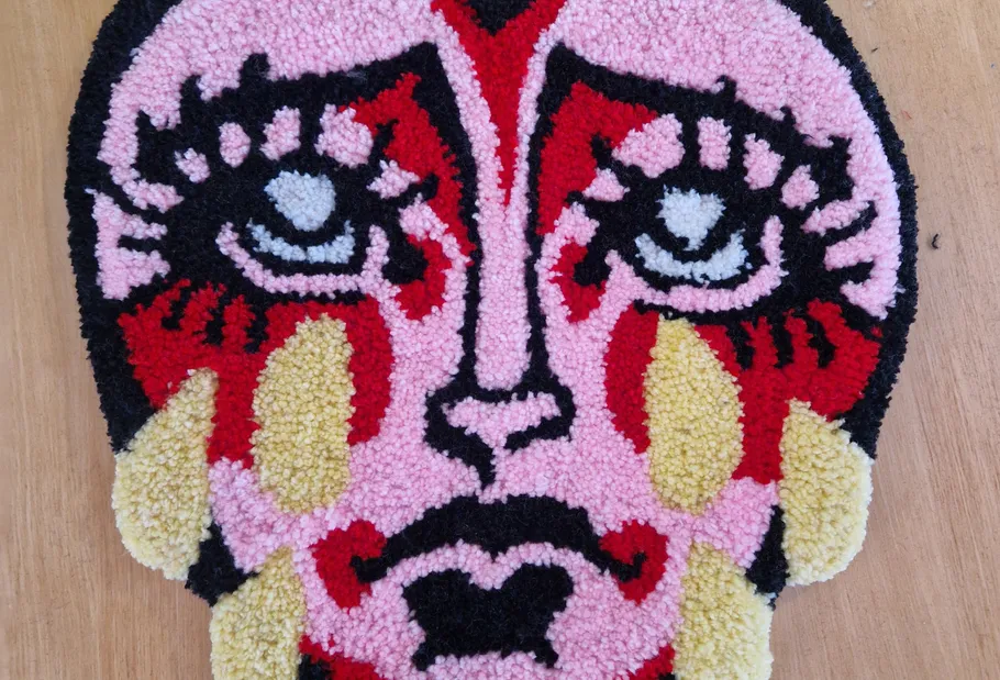 Colorful abstract face rug on wooden floor.