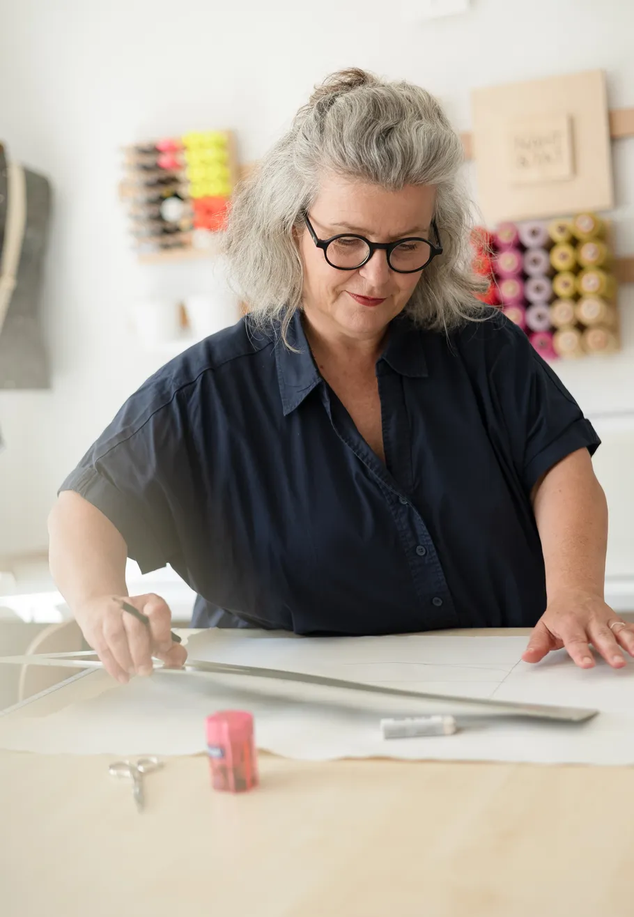 Woman measuring fabric in sewing room.
