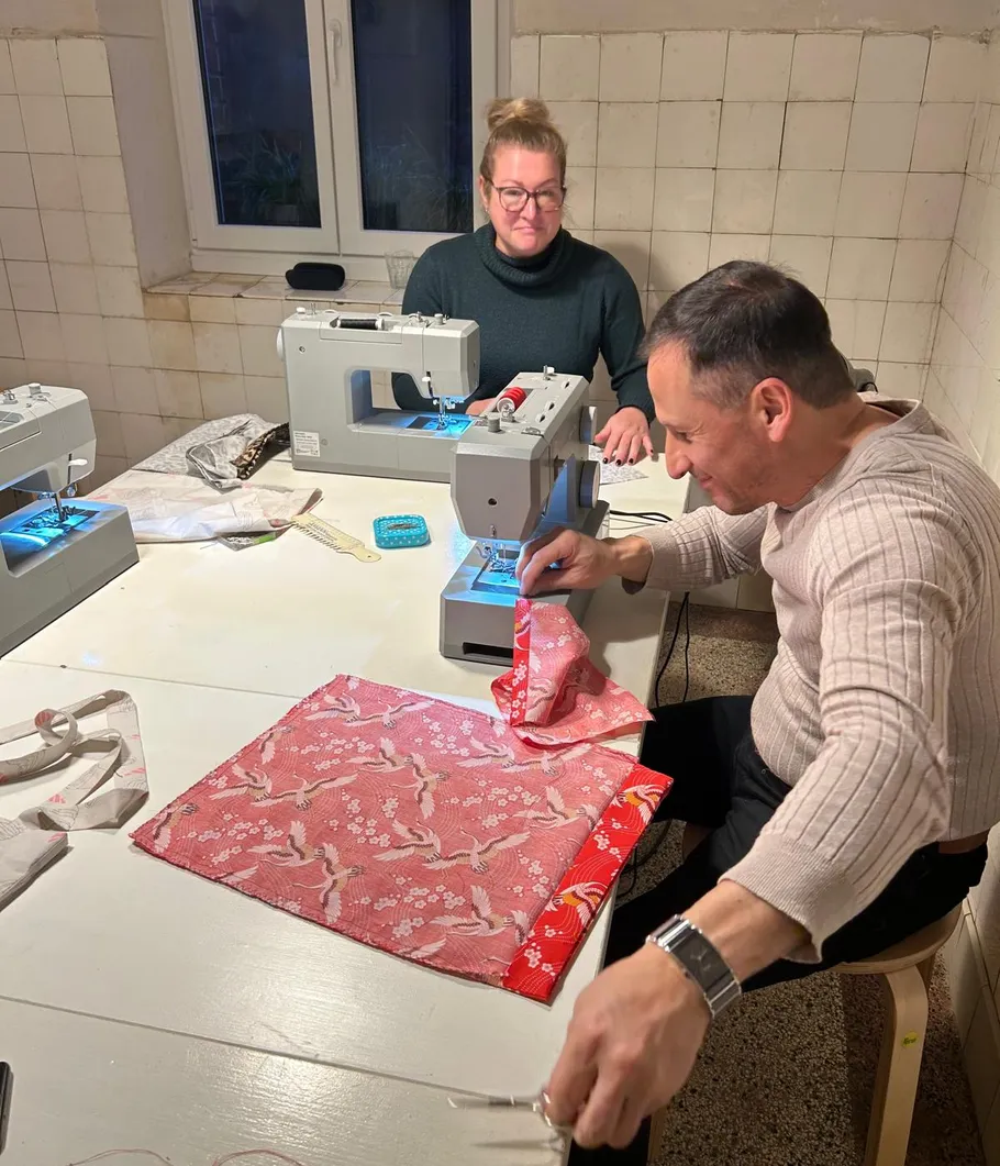 Two people sewing fabric on machines indoors.