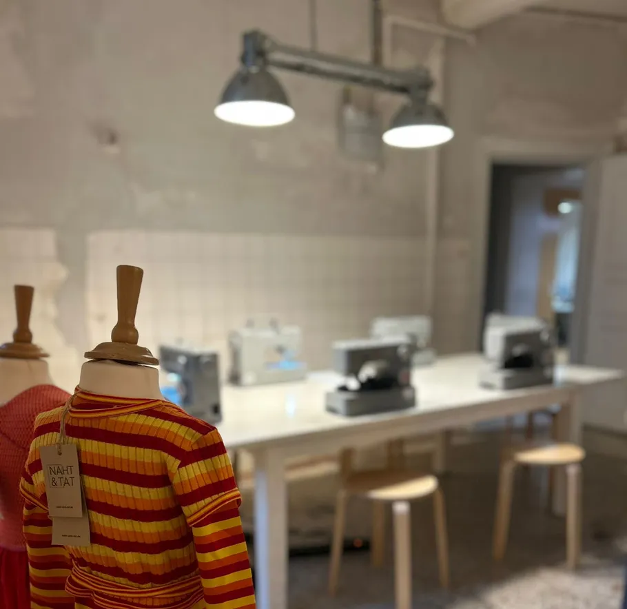 Mannequin in sewing room with machines, lights above.